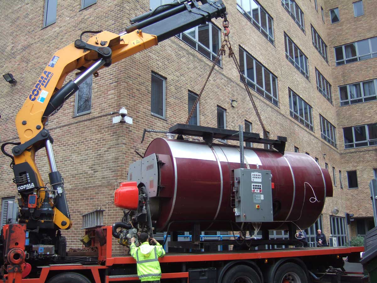 Industrial boiler removal loaded by crane onto specialist transport vehicle